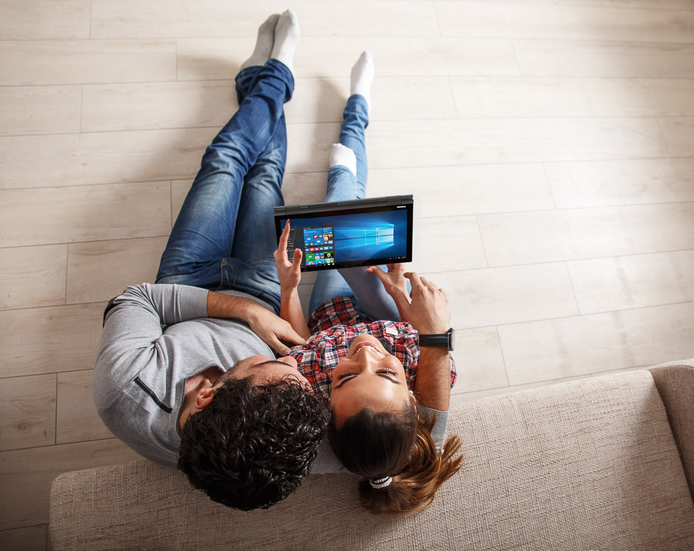 Young couple sitting on floor and using notebook.